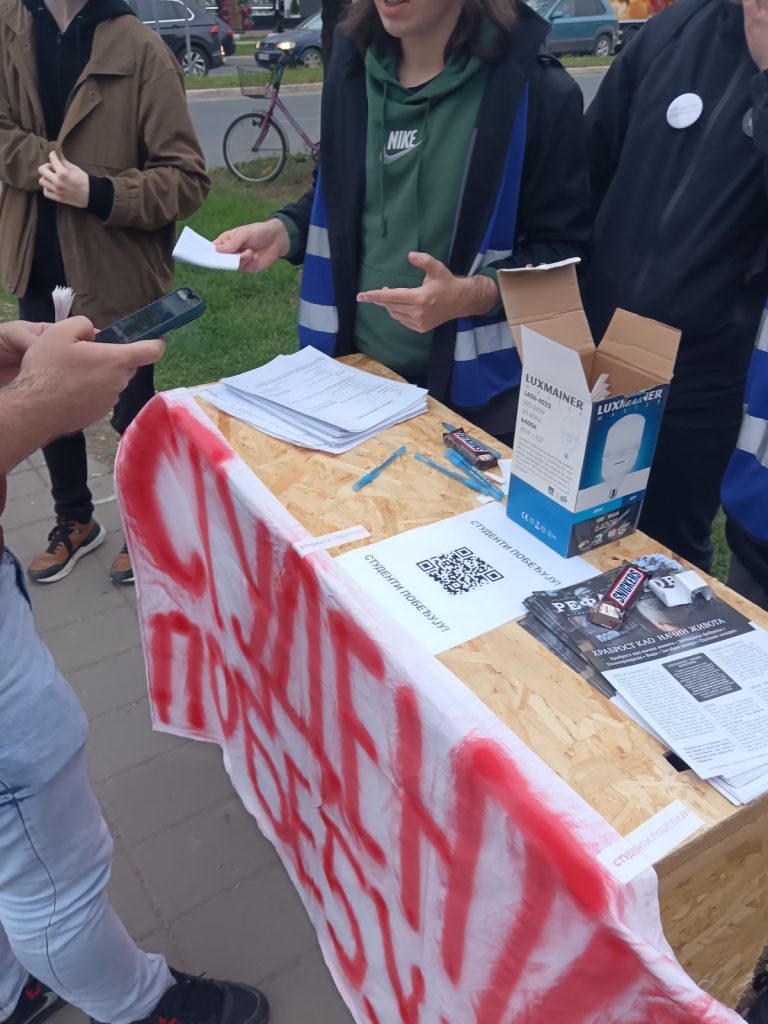 Studenti i građani tokom akcije deljenja nalepnica „Studenti pobeđuju“ u Staroj Pazovi na javnoj lokaciji